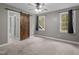 A spacious carpeted bedroom featuring a barn door, ceiling fan, and two windows bringing in natural light at 5600 Thornburg Dr, Wake Forest, NC 27587