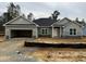 New construction home with an open garage, grey stone accents, green siding and dark roof at 37 Streamline Ct, Lillington, NC 27546