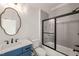 Charming bathroom boasts blue vanity, decorative mirror, and tiled shower/tub combo with sliding glass door at 617 Darian Woods Dr, Holly Springs, NC 27540