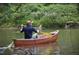 Personal paddles an orange canoe on the lake with green leafy trees and flowers at 252 Beacon Dr, Pittsboro, NC 27312