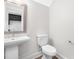 A half bath with a stand alone sink, toilet, light grey walls, and a decorative mirror at 324 Church St, Morrisville, NC 27560