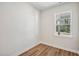 A bedroom with light wood-look flooring, white walls, white trim, and a window offering a view of the outside at 622 Brittany Ct, Durham, NC 27703