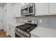 Close up of a kitchen featuring stainless steel appliances, white countertops, gray backsplash, and white cabinets at 622 Brittany Ct, Durham, NC 27703