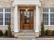 Elegant wooden front door with glass panels, flanked by white columns and manicured greenery at 2642 Marchmont St, Raleigh, NC 27608