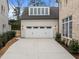 Attached two-car garage with paneled doors, featuring exterior lighting and upper dormer windows at 2642 Marchmont St, Raleigh, NC 27608
