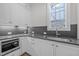 Modern kitchen features white cabinets, gray countertops, stainless steel appliances, and ample natural light at 2642 Marchmont St, Raleigh, NC 27608
