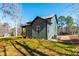 Side view of the house, green siding with black accents, and a backyard view with partial wooded scenery at 109 Lone Star Dr, Louisburg, NC 27549