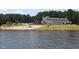 Scenic lake view featuring a sandy beach and community buildings, perfect for relaxation and outdoor activities at 169 Running Deer Dr, Louisburg, NC 27549