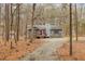 Gray house with red door, wood deck, and gravel driveway, nestled in a wooded area at 9100 Greenbriar Sta, Chapel Hill, NC 27516