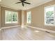 Bright bedroom with three large windows, wood-look flooring, and neutral paint at 142 Batten Hill Ln, Selma, NC 27576
