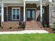 Inviting front porch with brick steps and iron railings on a home with stone accents at 142 Batten Hill Ln, Selma, NC 27576