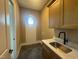 Bright laundry room features a sink, cabinet, countertop space, and a unique round window at 142 Batten Hill Ln, Selma, NC 27576