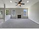 Bright living room featuring neutral paint, carpeted floors, a ceiling fan, and a fireplace with windows on either side at 6 Heatherford Ct, Durham, NC 27704