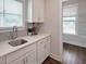 Bright laundry room with white cabinets, quartz countertops, and a utility sink at 8817 Melvin St # 27, Willow Springs, NC 27592