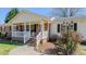Close-up of a charming covered porch featuring brick steps, a white railing, and decorative outdoor lighting at 2434 Orice St, Burlington, NC 27215