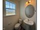 Bright powder room with pedestal sink, oval mirror, and natural light from the window at 424 La Maison Ave # 9, Wendell, NC 27591