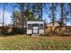 Backyard with a charming shed painted white with black trim, surrounded by trees at 46 Two Belles Ct, Angier, NC 27501