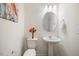 Bright powder room featuring a pedestal sink, oval mirror, and modern lighting fixture at 504 Morning Glade St, Wake Forest, NC 27587