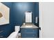 This blue bathroom features modern fixtures, an arched gold mirror, and elegant stone countertops at 3410 Bradley Pl, Raleigh, NC 27607