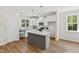 Bright kitchen boasts white cabinets, a gray island with granite countertops, and stainless appliances at 123 Wichita Way, Louisburg, NC 27549
