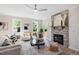 Cozy living room featuring a stone fireplace, modern ceiling fan, and large windows overlooking the outdoors at 123 Wichita Way, Louisburg, NC 27549