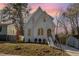 Stunning white brick home with landscaped yard and elegant arched windows set at dusk at 1409 Sedgefield St, Durham, NC 27705