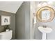 Cozy powder room featuring a pedestal sink, framed artwork, and stylish round mirror at 8204 Yaxley Hall Dr, Raleigh, NC 27616