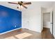 Bright bedroom with hardwood floors, modern ceiling fan, and a blue accent wall at 8204 Yaxley Hall Dr, Raleigh, NC 27616
