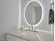 Bathroom featuring a modern, backlit, circular mirror and sleek countertop at 1309 Briar Patch Ln, Raleigh, NC 27615