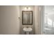 Stylish powder room featuring a pedestal sink, classic mirror, modern lighting and a view into the living room at 1825 Hinesley Dr, Durham, NC 27703