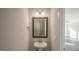 Modern powder room with pedestal sink, decorative mirror, sconce lighting, and doorway to the living room at 1825 Hinesley Dr, Durham, NC 27703
