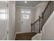 Bright foyer featuring hardwood floors, staircase with dark metal railing, and a white front door at 1825 Hinesley Dr, Durham, NC 27703