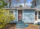 Exterior view of small blue cottage and front steps surrounded by landscaping at 417 Elm St, Raleigh, NC 27604