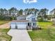 Two-story home featuring a manicured lawn, a three car garage, and a charming front porch at 155 Shelby Meadow Ln, Angier, NC 27501