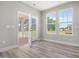 Bright living room with wood-look floors, a large window, and French doors to the screened-in porch at 155 Shelby Meadow Ln, Angier, NC 27501