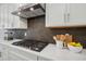 Close up of kitchen features sleek black gas cooktop, white marble countertops, and stylish backsplash at 2229 Abbeyhill Dr # 123, Raleigh, NC 27610