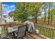 The outdoor wooden deck features comfortable outdoor seating and a BBQ grill with wooded views at 3236 Forest Mill Cir, Raleigh, NC 27616