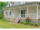 Charming home entrance with a welcoming porch, staircase, and flower landscaping at 7039 Old 421 Rd, Liberty, NC 27298