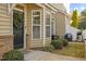 Close-up of a welcoming front door adorned with a wreath, complemented by charming bay windows and outdoor seating at 1120 Renewal Place # 108, Raleigh, NC 27603