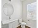Well-lit powder room showcasing pedestal sink, round mirror and window for natural light at 1204 Holding Village Way, Wake Forest, NC 27587