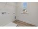 Bright laundry room featuring wood-look floors, utility sink, shelving, and a window for natural light at 199 Shelby Meadow Ln, Angier, NC 27501