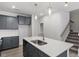 Modern kitchen featuring gray cabinets, stainless steel appliances, quartz countertop island, and open staircase at 281 Chesapeake Commons St # 95, Garner, NC 27529