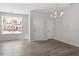 An airy living area with neutral walls, gray wood floors, and a charming light fixture with backyard view at 281 Chesapeake Commons St # 95, Garner, NC 27529
