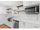 Bright kitchen featuring white cabinets, stainless appliances, and a view to the modern living space at 6512 Johnsdale Rd, Raleigh, NC 27615