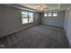 Large primary bedroom with carpeted floor, ceiling fan, tray ceiling, and a large window with a neighborhood view at 8 Steppe Way, Garner, NC 27529