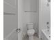 A minimalist bathroom features a toilet and a shower/tub combination with white tiling and neutral-toned flooring at 1721 Burnette Garden Path, Raleigh, NC 27612