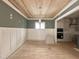 A dining area featuring wood floors, wainscoting, a wood ceiling, and seamlessly connects to the modern kitchen at 1721 Burnette Garden Path, Raleigh, NC 27612