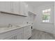 Bright laundry room with white cabinets, gray tile flooring and a large window at 1721 Burnette Garden Path, Raleigh, NC 27612
