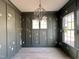 A refined room design enhanced by elegant wainscoting, dark walls, stylish chandelier, and bright windows at 1721 Burnette Garden Path, Raleigh, NC 27612