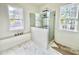 A bathroom features a glass shower, a marble tub, and serene views from large windows at 1721 Burnette Garden Path, Raleigh, NC 27612